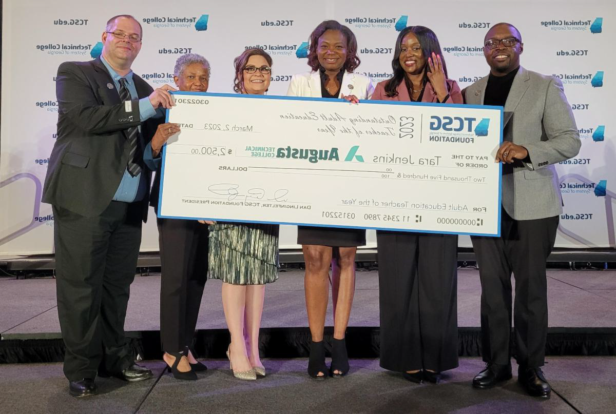 Dr. Whirl, the president of Augusta Technical College, stands with the 2022 and 2023 Adult Education Teacher of the Year winners as well as the 2022 EAGLE winner and Dean Moseley while holding the check from TCSG.