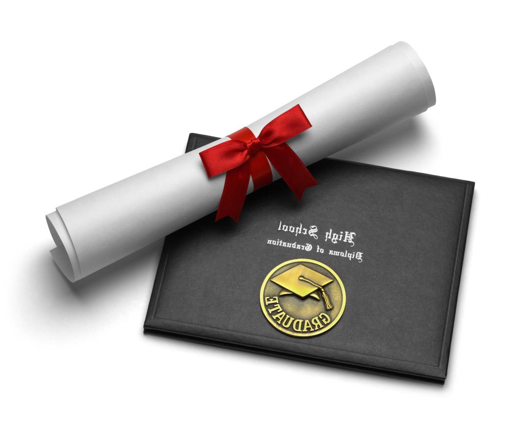 A high school diploma tied with a red ribbon lays diagonally across a black diploma holder with the words High School Diploma of Graduation in white stylized font above a gold seal with a graduation cap and the word graduate in all capitalized letters.